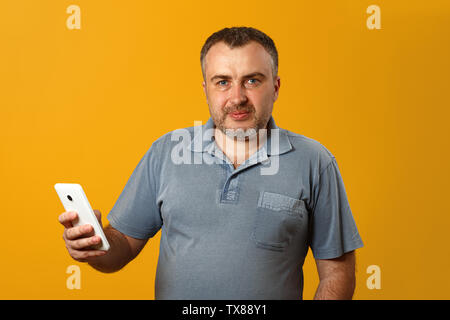 Attractive young man with smartphone on yellow background Stock Photo