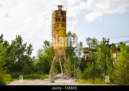 Fallen rusty industry concept photo in the abandoned cement factory with aged grunge concrete and metal strucures. Stock Photo