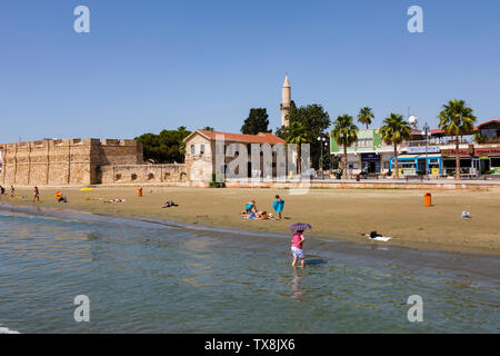 Bathers on the beach at Finikoudis, with the Fort and Mosque in the background. Larnaca, Cyprus. Stock Photo