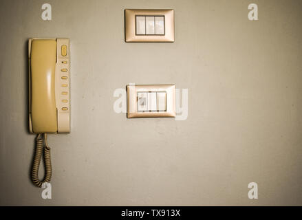 Vintage hotel room facilities. Old switches and antique phone on the white wall. Stock Photo