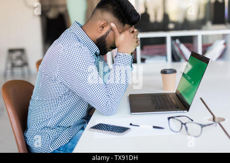 Tired and worried indian business man at workplace in office Stock Photo