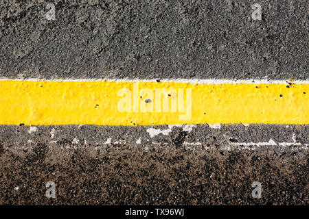 The yellow line is drawn on the asphalt gray tint. The line separates the two parts of the pavement. Stock Photo
