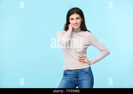 studio portrait of a beautful caucasian woman, looking at camera smiling, isolated on blue background Stock Photo