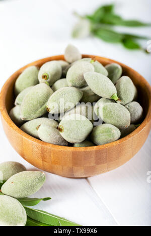 Fresh green almonds in a wooden bowl on white background. Stock Photo