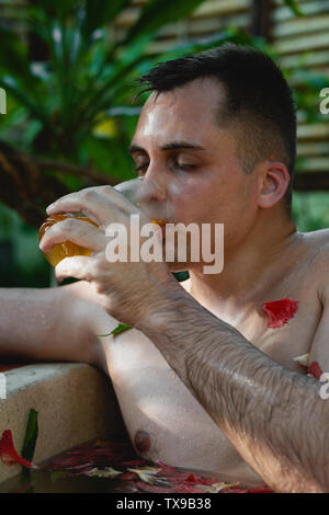The guy takes a herbal bath in the spa and drinks ice tea Stock Photo