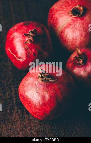 Four ripe pomegranate on rustic wooden table Stock Photo