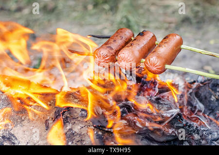 Grilling sausages over an open fire outdoors Stock Photo