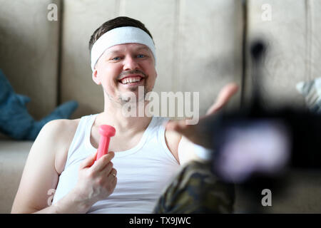 Male vlogger holds dumbbells in his hands and shouts at the camera on his subscriber, motivating them to action. Tutoring grade on an individual progr Stock Photo