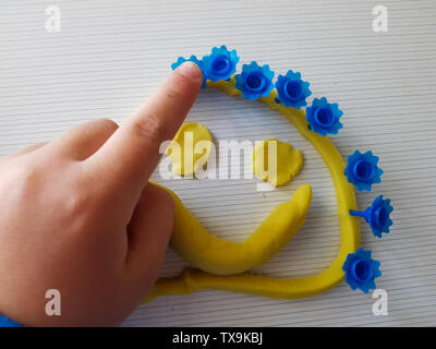 Fanny face made of a modeling clay. Mede by child. Stock Photo