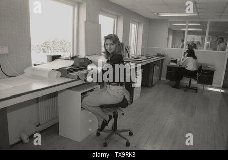 1980s, a young female in a bright design office with a wooden floor sitting on a swivel chair by a large window, working on a type of electronic data processor with a keyboard and sitting on top of it, a GSi scanner or laser printer, England, UK. Stock Photo