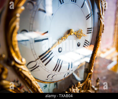 Closeup detail of ancient stylish wall watch, golden pointers on white dial Stock Photo