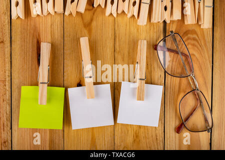 Colorful sticky notes hung on wooden clips. Sticky notes for saving reminders on a wooden table. Light background. Stock Photo