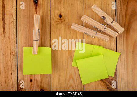 Colorful sticky notes hung on wooden clips. Sticky notes for saving reminders on a wooden table. Light background. Stock Photo