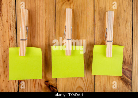 Colorful sticky notes hung on wooden clips. Sticky notes for saving reminders on a wooden table. Light background. Stock Photo