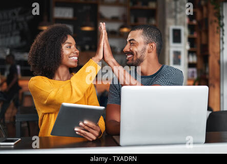 Friends in cafe giving high five to each other Stock Photo