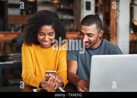 Smiling couple looking at mobile phone in café Stock Photo