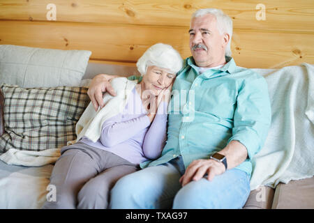 Senior man in casualwear sitting on couch and watching tv program Stock Photo