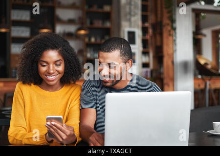 Man looking at his girlfriend's mobile phone in cafe Stock Photo