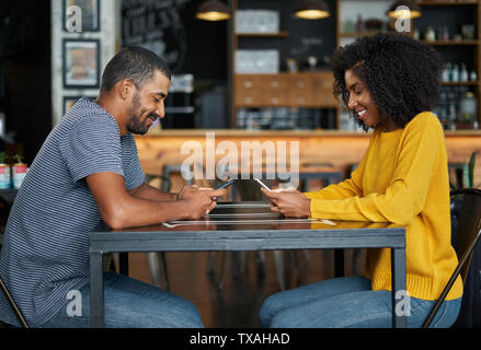Couple at cafe table using mobile phones Stock Photo