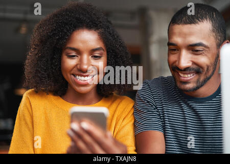 Smiling african couple looking at cellphone Stock Photo