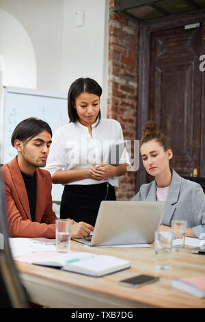 Portrait of multi-ethnic business team using laptop together while collaborating on startup project in office, copy space Stock Photo