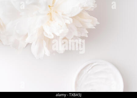 White peony and mockup face and body cream on white background. Cosmetics concept. Flat lay. Stock Photo