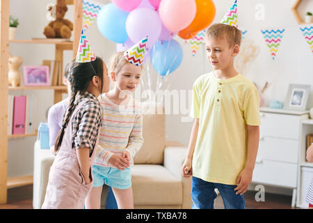 Group of cute little kids in birthday caps discussing rules of new game Stock Photo