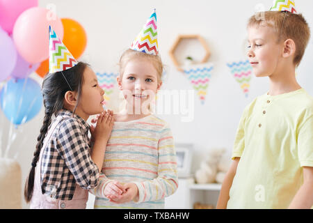 Cute little girl whispering something to one of her friends Stock Photo