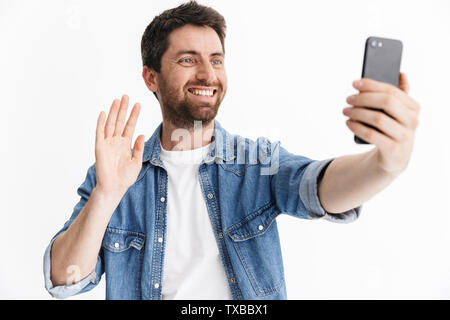 Portrait of a handsome bearded man wearing casual clothes standing isolated over white background, taking a selfie Stock Photo