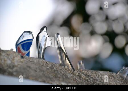 Jagged shards of smashed glass from bottles cemented on top of a wall to provide security from intruders Stock Photo