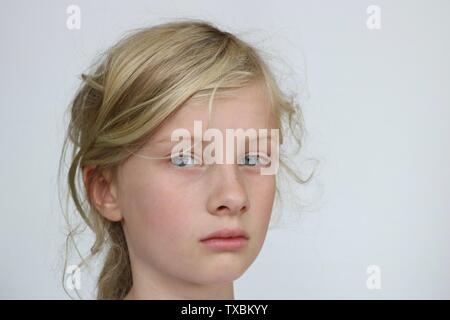 Portrait of a pre adolescent unhappy girl looking at the camera against a white background Stock Photo