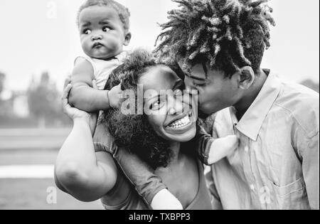 Happy African family having fun in a park outdoor - Mother and father with their daughter enjoying time together in a weekend day Stock Photo