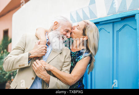 Happy fashion senior couple dating outdoor - Mature elegant older people celebrating date of their anniversary - Wife kissing her husband Stock Photo