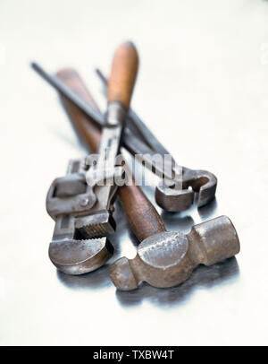 Selective focus background image of rustic old mechanic tools on light reflective steel background. Stock Photo