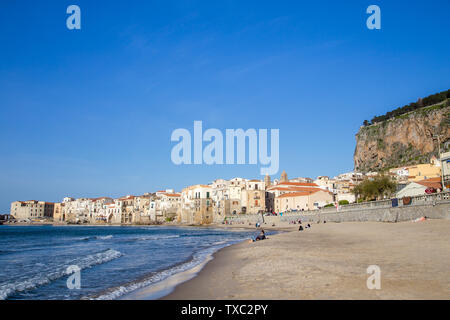 Céfalu, Sicily, Italy - March 16, 2018: a relaxing sunny day at the beach of Céfalu, with few unrecognisable people and old typical buildings Stock Photo