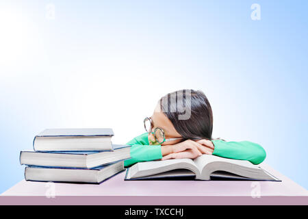 Asian cute girl with glasses fall asleep on book on the desk over bright background Stock Photo