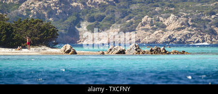 An unidentified couple are sunbathing on the beautiful Cavalieri beach (Spiaggia di Cavalieri) bathed by a turquoise clear sea. Maddalena Archipelago Stock Photo