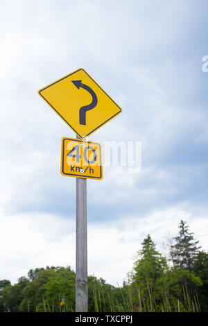 Road Signs Showing Speed Limit 40 km/h And Turn Ahead Left Bend Stock Photo