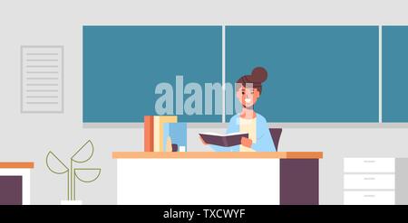 smiling teacher sitting at desk woman checking students copybook in front of green chalk board education concept modern classroom interior flat Stock Vector