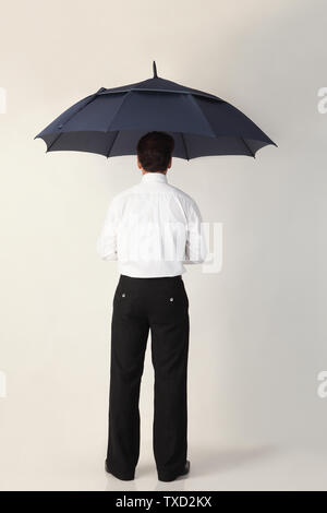Rear view of a man standing under an umbrella Stock Photo