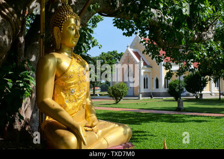 A Buddha statue at Wat Niwet Thammaprawat, a temple adjoining Bang Pa-In Palace, Bang Pa-In, Thailand, a European-style  temple bldg. in the b/g Stock Photo