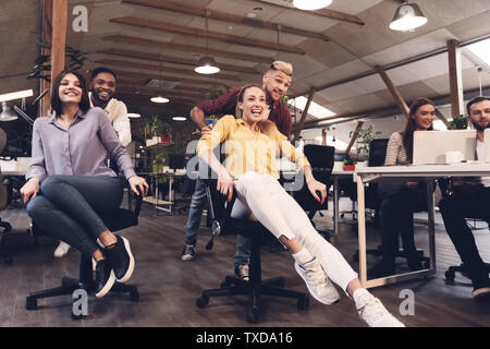 Business team of software developers having fun, racing on office chairs Stock Photo