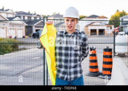 Young construction worker putting on his safety gear at a job site. Stock Photo
