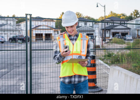 Happy construction foreman talking with an employee on his cell phone. Stock Photo