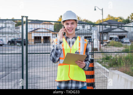 Happy construction foreman talking with an employee on his cell phone. Stock Photo