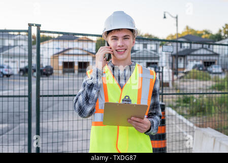 Happy construction foreman talking with an employee on his cell phone. Stock Photo