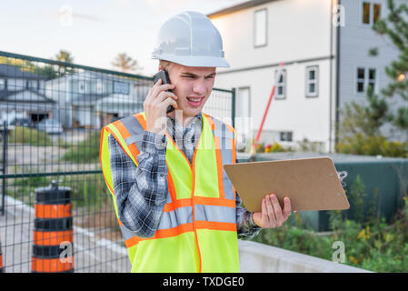 Frustrated construction foreman talking with an employee on his cell phone. Stock Photo