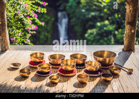 Tibetan singing bowls on a straw mat against a waterfall Stock Photo