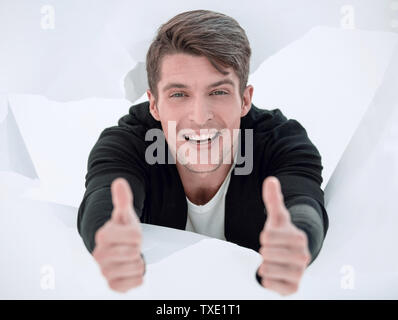 man breaking through paper wall and showing thumbs up Stock Photo