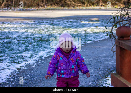 20 months old baby enjoying the nice weather outside. Toddler girl portraits in natural light. Little girl close up picture in nature, in Winter Stock Photo